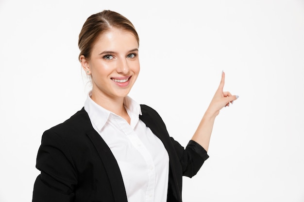 Femme d'affaires blonde souriante pointant vers l'arrière