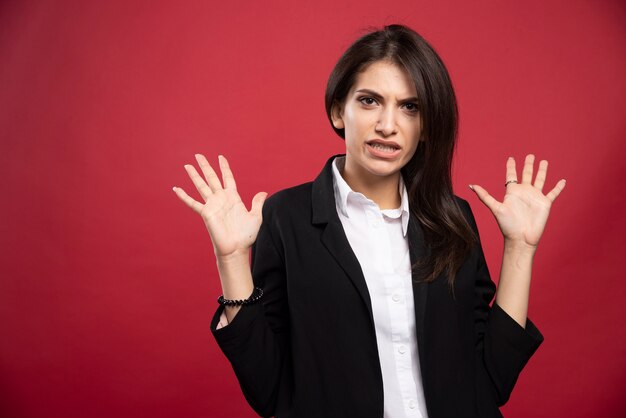 Femme d'affaires brune debout en colère sur fond rouge.