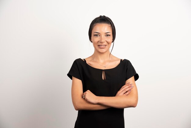 Femme d'affaires brune debout sur un mur blanc.