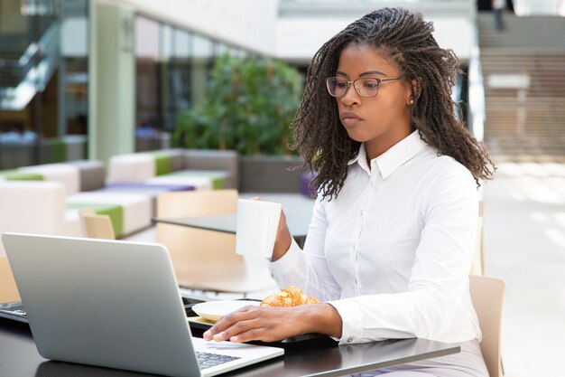 Femme d'affaires ciblée, boire du café tout en travaillant