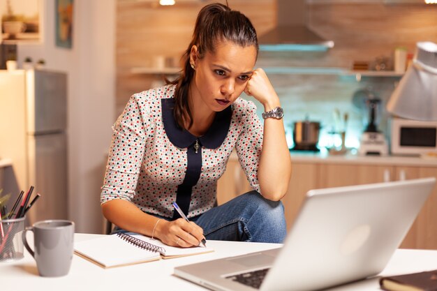 Femme d'affaires concentrée essayant de terminer un projet de travail pendant minuit. Employé utilisant la technologie moderne à minuit faisant des heures supplémentaires pour le travail, les affaires, occupé, carrière, réseau, style de vie, sans fil