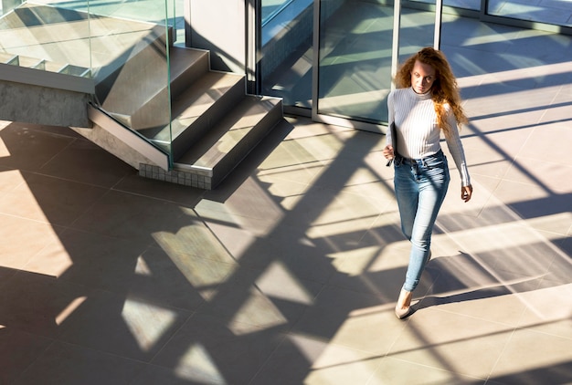 Femme d'affaires confiante marchant dans le bâtiment long shot