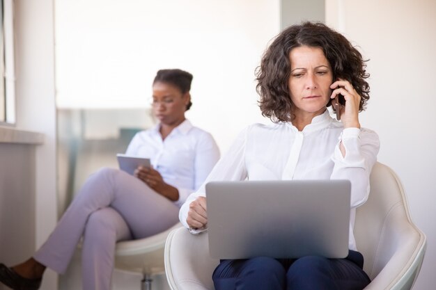 Femme d'affaires confuse parlant au téléphone