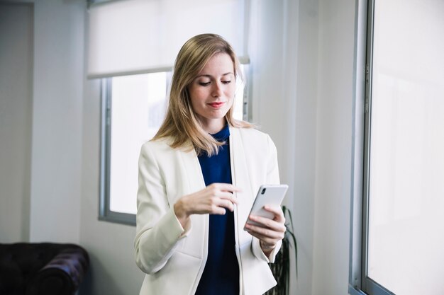 Femme d&#39;affaires de contenu en regardant smarphone