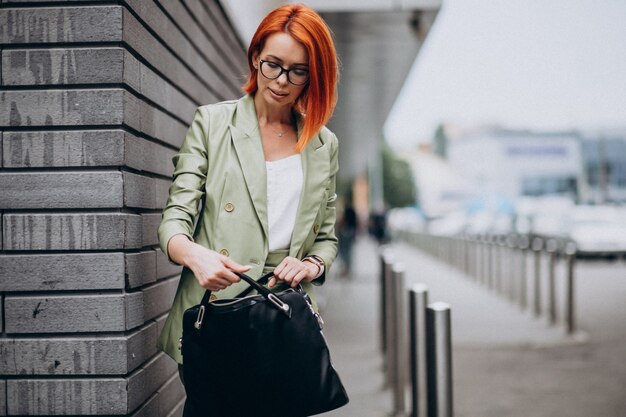 Femme d'affaires en costume vert debout près du mur