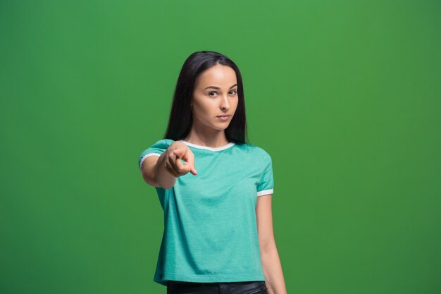 La femme d'affaires dominatrice vous pointe et vous veut, portrait gros plan demi-longueur sur fond vert.