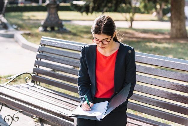 Photo gratuite femme d'affaires écrit sur un banc