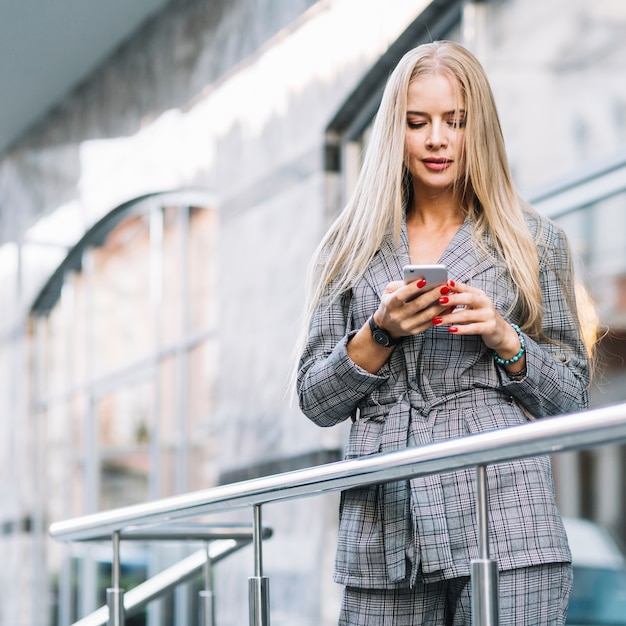 Photo gratuite femme d'affaires élégant à l'aide de smartphone en ville