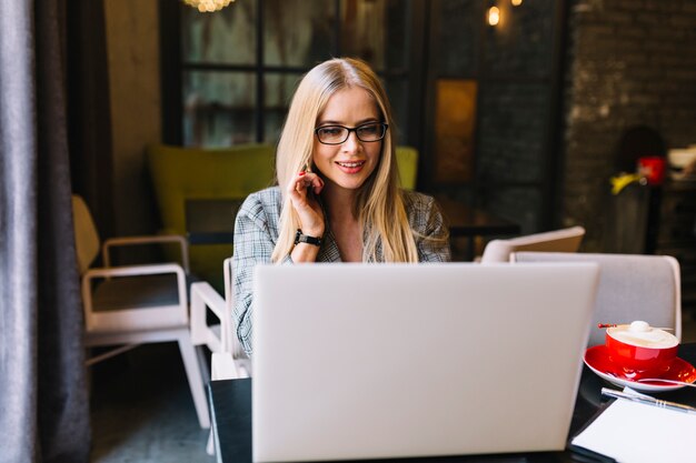 Femme d&#39;affaires élégant avec un ordinateur portable dans un café confortable