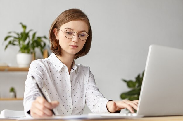 Femme d'affaires élégante habillée formellement assis avec un ordinateur portable