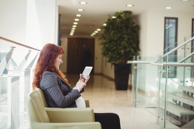 Femme d'affaires enceinte à l'aide de tablette numérique près du couloir