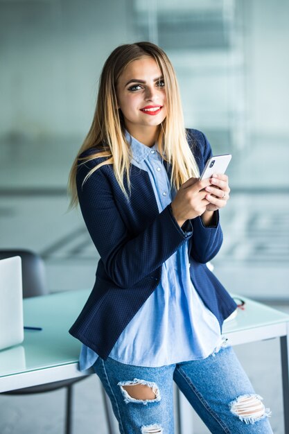 Femme d'affaires envoyant un message avec smartphone au bureau