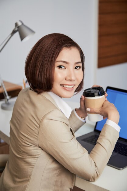 Femme d'affaires ethnique joyeuse avec café