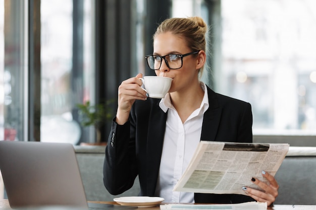 Femme d'affaires graves lisant le journal.