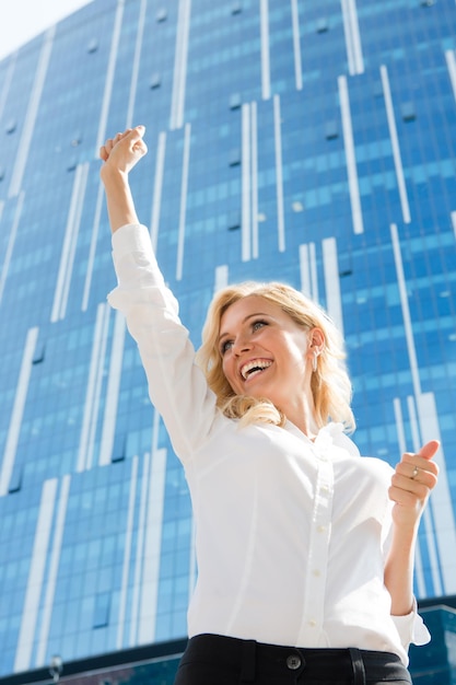 Une femme d'affaires heureuse est la gagnante. Belle dame en blouse blanche a levé la main et souriant à cause du succès.