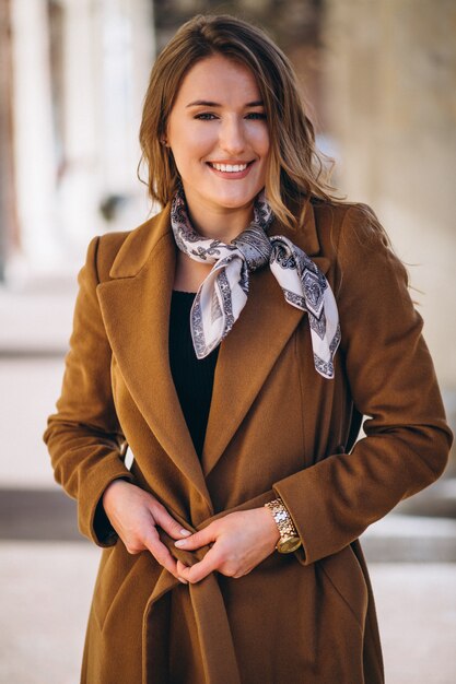 Femme d&#39;affaires heureuse en manteau dans la rue