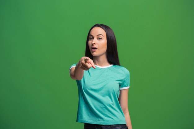 La femme d'affaires heureuse vous pointe et vous veut, portrait gros plan demi-longueur sur vert.