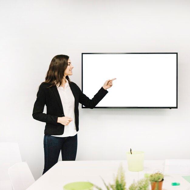 Femme d&#39;affaires heureux pointant vers un écran blanc blanc