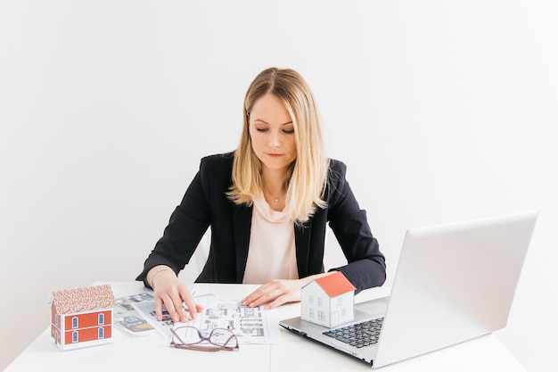 Femme affaires, implantation, devant, ordinateur portable, regarder, blueprint, au bureau