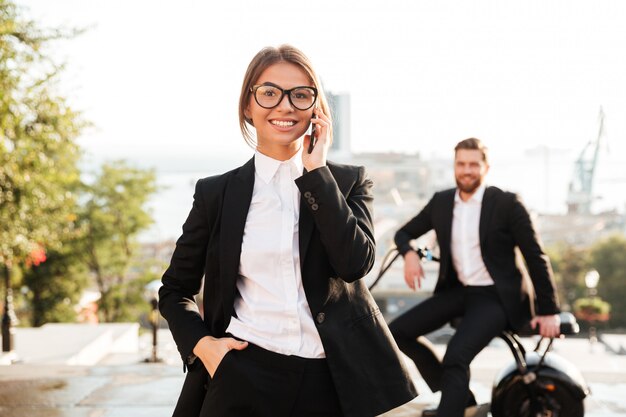 Femme d'affaires insouciante posant à l'extérieur et parlant par téléphone