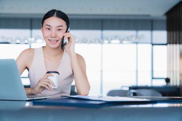 Photo gratuite une femme d'affaires intelligente asiatique travaille et communique avec un smartphone et un ordinateur portable avec bonheur et fraîcheur