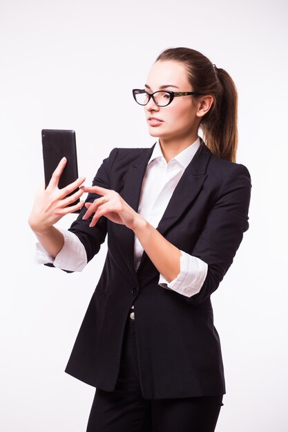 Femme d'affaires jeune, confiante, réussie et belle avec l'ordinateur tablette isolé sur un mur blanc