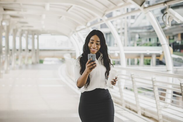 Femme d&#39;affaires jeune regardant sur son téléphone portable pendant le travail au travail.