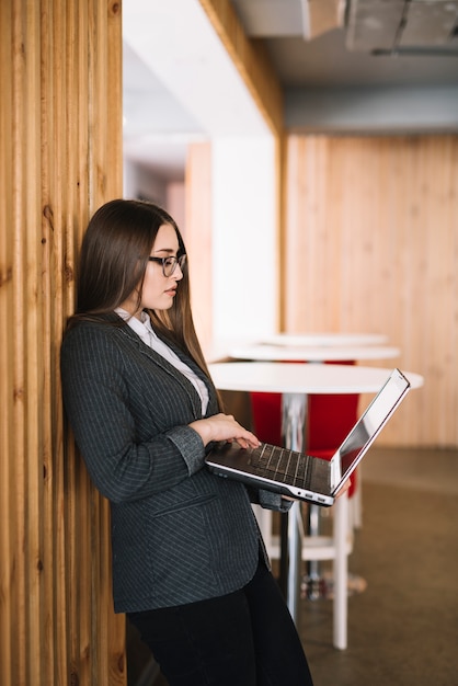 Femme d&#39;affaires jeune tapant sur un clavier d&#39;ordinateur portable au mur