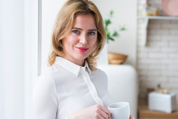 Femme d&#39;affaires jolie blonde debout avec une tasse de café