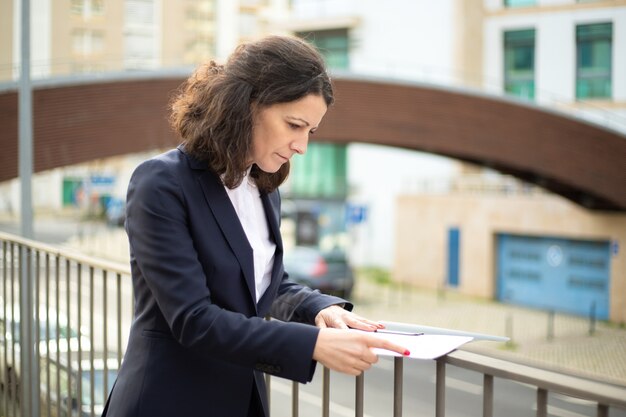 Femme affaires, lecture, papiers, rue