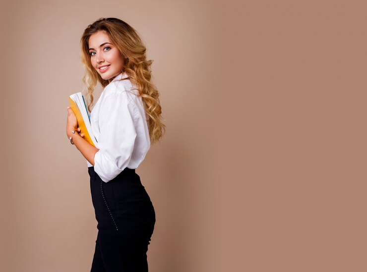 Photo gratuit femme d'affaires à lunettes élégantes debout sur un mur beige. cheveux ondulés blonds. chemisier blanc et pantalon noir.