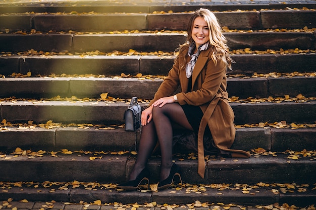 Femme d&#39;affaires en manteau assis sur les escaliers