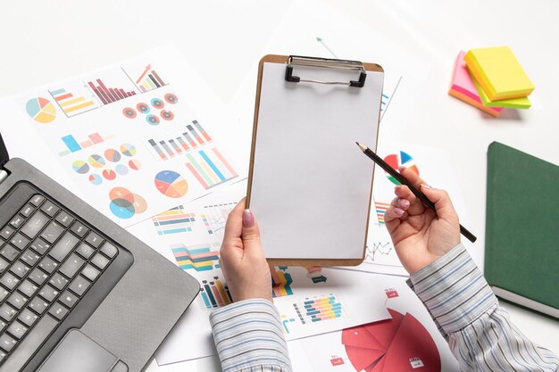 Femme d'affaires marketing en chemise rayée au bureau avec ordinateur écrit dans le bloc-notes