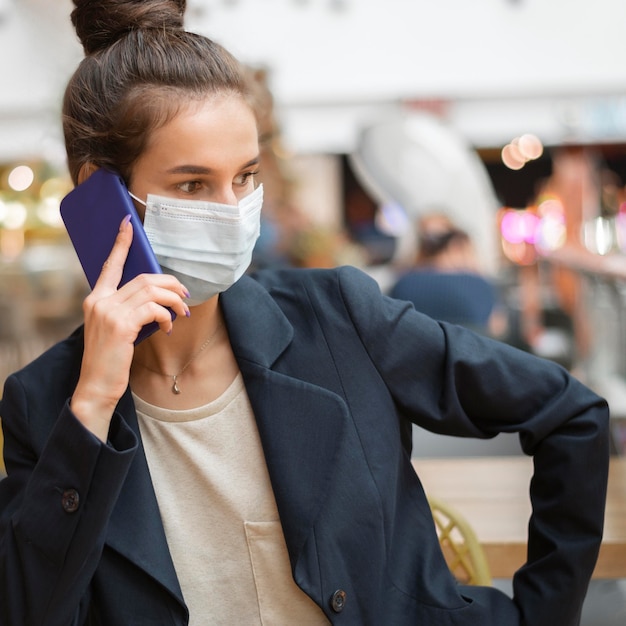 Femme d'affaires avec masque médical parlant à son téléphone