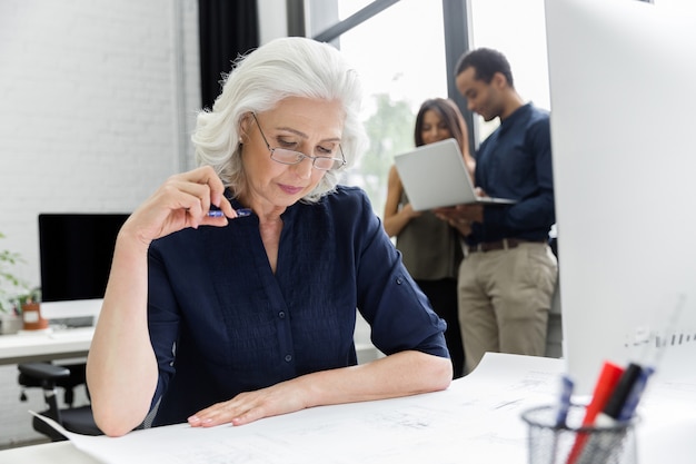 Femme d'affaires mature travaillant avec des documents tout en étant assis sur son lieu de travail