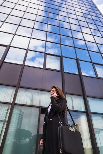 Femme d&#39;affaires en noir parlant par téléphone à l&#39;extérieur