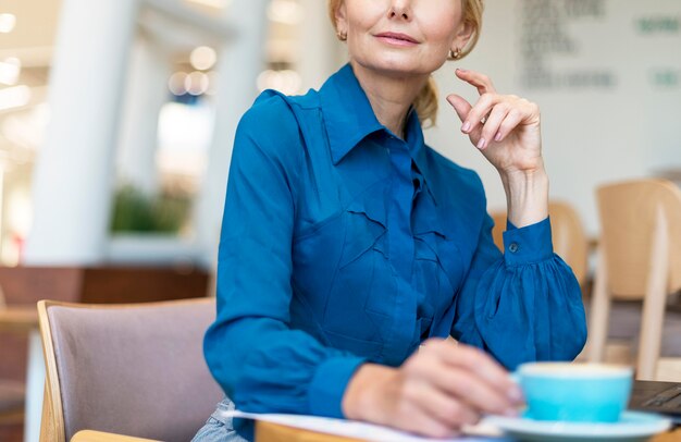 Femme d'affaires plus âgée prenant un café tout en travaillant