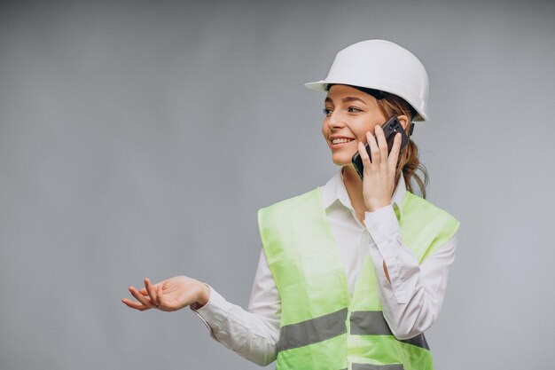 Femme d'affaires portant un gilet et un casque parlant au téléphone