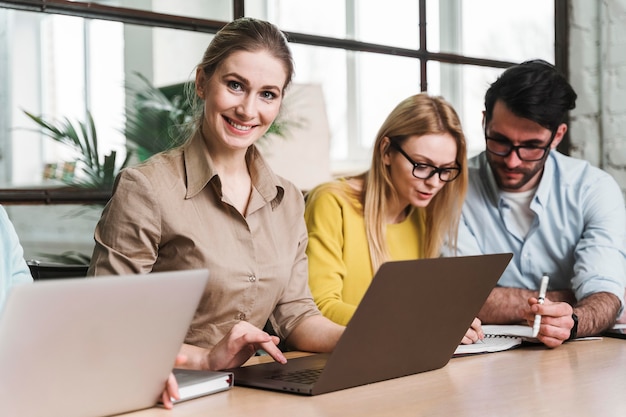 Femme d'affaires posant lors d'une réunion à l'intérieur avec ordinateur portable