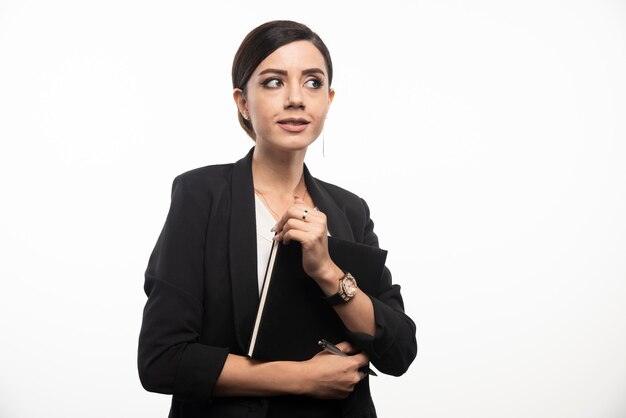 Femme d'affaires posant avec un ordinateur portable sur un mur blanc.