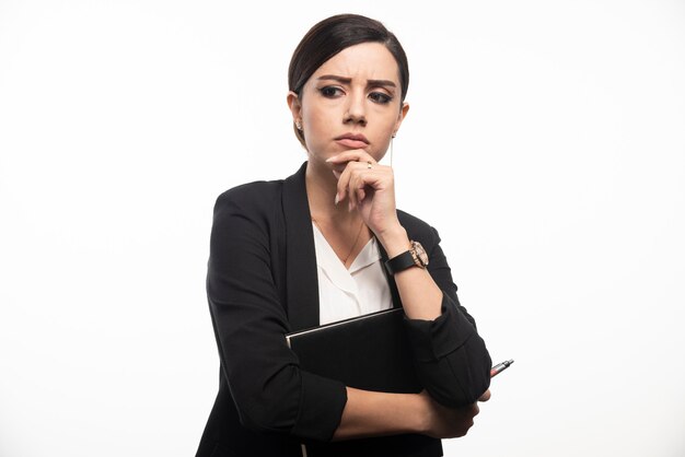 Femme d'affaires posant avec un ordinateur portable sur un mur blanc.