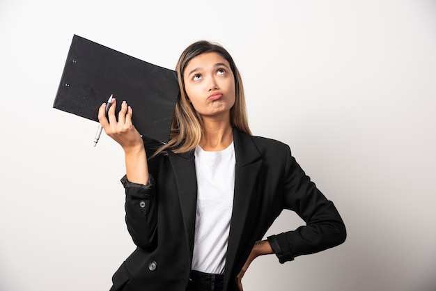 Femme d'affaires posant et tenant le presse-papiers.