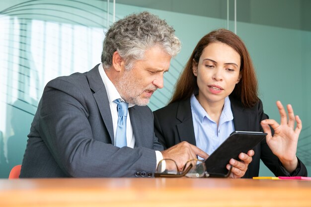 Femme d'affaires présentant le projet à l'investisseur. Employée sérieuse montrant le contenu sur tablette à un collègue, expliquant les détails.