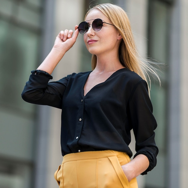 Photo gratuite femme d'affaires professionnelle posant en costume et lunettes de soleil à l'extérieur