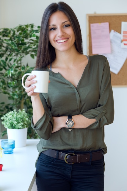 Femme d&#39;affaires qui boit du café dans son bureau.