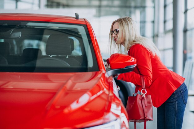 Femme d'affaires à la recherche d'un mobile auto dans une salle d'exposition de voitures