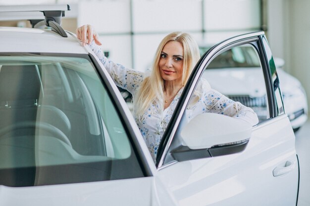 Femme d'affaires à la recherche d'un mobile auto dans une salle d'exposition de voitures