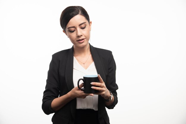 Femme d'affaires à la recherche d'une tasse noire sur fond blanc. photo de haute qualité