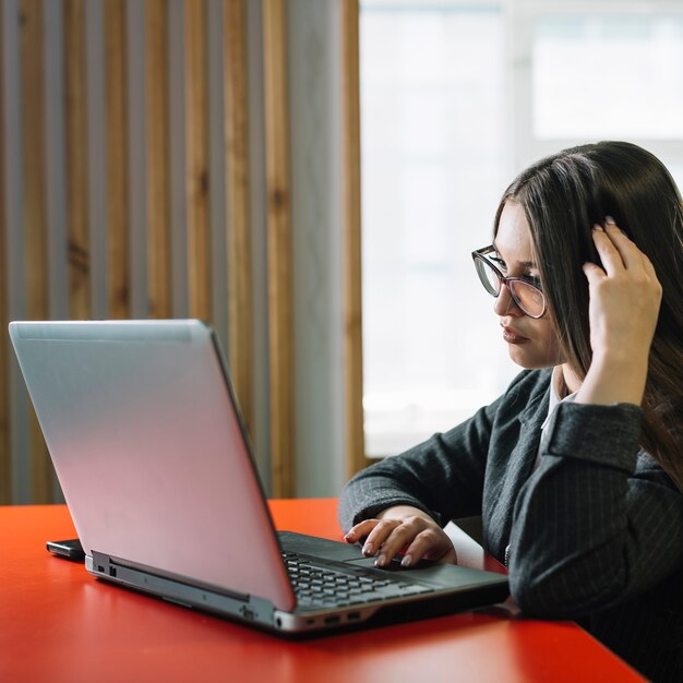 Femme d&#39;affaires réfléchie à l&#39;aide d&#39;un ordinateur portable à la table