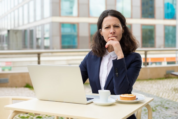 Femme d'affaires réfléchie avec ordinateur portable à la recherche